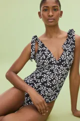 Traje de baño enterizo negro con estampado floral blanco, escote en V y breteles con moños.