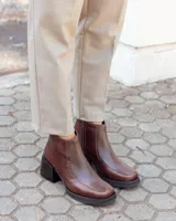 Botinetas de cuero color chocolate, con diseño de textura tipo reptil en el empeine y laterales. Presentan un taco cuadrado de altura media, suela de goma negra y cierre lateral para mayor comodidad.