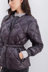 Campera de nylon color berenjena con relleno de pluma, corte regular, cierre doble en delantero y bolsillos. Cinturón elástico gofrado en la espalda y mangas largas con elástico en puños.