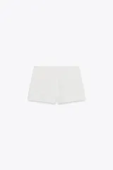 Shorts tiro bajo color negro con bolsillos delanteros. Cierre frontal con cremallera y ganchos metálicos.