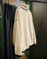 Buzo beige de pana con cuello alto forrado en corderito blanco, cierre parcial con cremallera, puños y cintura elastizados.