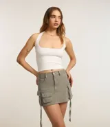 Minifalda color verde militar confeccionada en sarga de algodón. Cuenta con trabillas en la cintura, bolsillos cargo laterales con detalle de canalé colgando y cierre frontal tradicional.