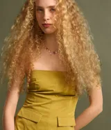 Blusa sin breteles color amarillo mostaza, confeccionada en sarga, con cierre por cremallera invisible en el lateral y bolsillos con solapa en la parte del frente. Posee lastex en la espalda y bajo redondeado.