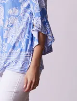 Blusa azul con estampado floral blanco, de seda fría, con cuello redondo con abertura y mangas 3/4 amplias con volados. Marca Ruby Rd.