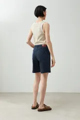 Bermuda azul marino de corte recto, con cinco bolsillos y cierre frontal con botón y cremallera.