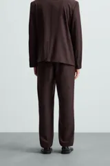 Pantalón de vestir color marrón oscuro, de corte recto, con bolsillos laterales y traseros de doble vivo. Se ajusta a la cintura con cierre de cremallera y botón.