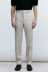 Pantalón de traje de lino color beige, corte slim fit, con cierre y corchete oculto, bolsillos laterales y traseros ribeteados.