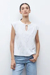 Remera verde petróleo con cuello redondo y abertura en forma de lágrima en el escote. Presenta un estampado geométrico en relieve y mangas cortas.