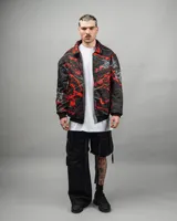 Campera reversible negra con estampado abstracto en rojo y blanco, de corte amplio y cuello camisero.