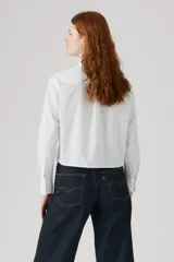 Camisa cropped blanca de manga larga con detalles de volados y pliegues verticales en el frente.