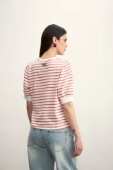 Remera de manga corta con cuello redondo y estampado de rayas horizontales blancas y negras. Mangas abullonadas con puño blanco.