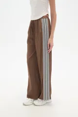 Pantalón de algodón negro, holgado, de calce medio, con cintura elástica y cordón ajustable. Presenta tres rayas blancas verticales en los laterales.