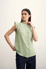 Camisa color amarillo pálido con cuello mao, sin mangas, con volados en los hombros y en el frente.