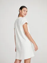 Vestido corto color crema, de corte recto y mangas cortas con bolsillo en el pecho.