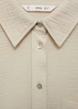 Camisa color crema de bambula, con cuello camisero, manga larga con puños abotonados, bolsillo de parche en la parte delantera, diseño oversize y cierre delantero con botones.