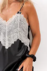 Camisón corto negro de satén con breteles finos y escote en V con puntilla blanca.