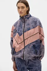 Campera estilo olímpica de jean con lavado gastado en azul y rosa. Corte oversized, con elástico en la cintura y bolsillos al frente con cierre.