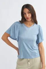 Remera celeste de viscosa con escote en V y mangas cortas tipo mariposa con detalle de bordado blanco en el escote.