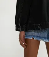 Chaqueta de jean negra, corte alargado, con cuello solapa, manga larga, abotonado frontal, bolsillos delanteros y laterales.