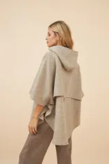 Capa amplia color beige con capucha, cierre metálico y bolsillos delanteros. Espalda con canesú y botones laterales para generar la manga. Confeccionada en lana fina sin teñir.