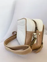 Bandolera rectangular color crudo y marrón, con correa larga regulable, cierre superior con cremallera y bolsillo interior. Fabricada en cuero con forro de tela.