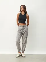 Pantalón jean gris de corte recto, con bolsillos laterales y tobillos ajustados con elástico.