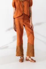 Pantalón de lino color naranja, de tiro medio y pierna recta, con detalle de crochet tejido a mano en el ruedo.