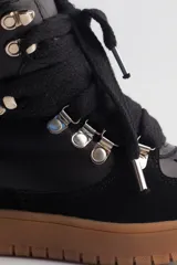 Zapatilla urbana negra de caña alta con plataforma, cordones y detalles de cuero y gamuza.
