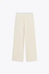 Pantalón de tiro alto color crema, con cintura combinada a contraste tipo boxer con cordones ajustables. Detalle de pinzas en delantero, bolsillos laterales y falso bolsillo de vivo en espalda.