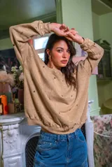 Sweater blanco de algodón con cuello redondo y mangas largas. Decorado con tachas plateadas en el frente y las mangas.