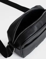Bandolera negra de cuerina con correa regulable desmontable, cierre superior, bolsillo frontal y tag de metal.