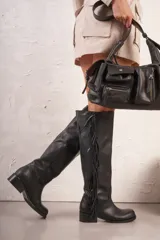 Bota alta de cuero negro con taco bajo y detalle de flecos en el lateral exterior.