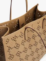 Cartera tote Tommy Hilfiger, color beige, con diseño calado del monograma TH en toda la superficie. Tiene doble asa de hombro, cierre magnético y amplio compartimento principal.