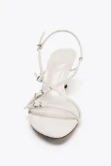 Sandalia de tacón color blanco con tiras finas cruzadas y detalles de hebillas metálicas.