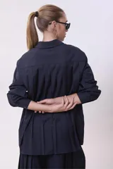 Camisa blanca de corte oversize, con cuello clásico y mangas largas con puños abotonados.