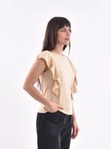 Remera blanca de cuello redondo con detalle de volados que nacen en los hombros y bajan por el frente.