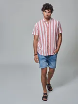 Camisa de hombre de manga corta, confeccionada en lino con rayas verticales blancas y ladrillo. Tiene cuello abotonado y bolsillo en el pecho.