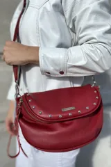 Bandolera de cuero color rojo con correa regulable de cinta, forrada en tela de algodón, cierre central y bolsillo con cierre atrás.