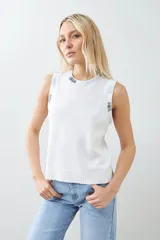 Chaleco tejido color crudo con cuello redondo y bordado multicolor en cuello y sisas.