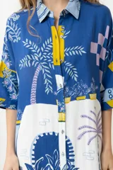 Vestido camisero corto con estampado de paisaje en tonos azules y amarillos.