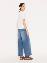 Pantalón de jean azul de corte ancho, estilo wide leg cropped, con lavado clásico y detalles de desgaste.