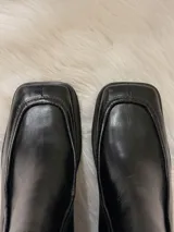 Botas de cuero negras con punta cuadrada, taco bajo de madera y cierre lateral.