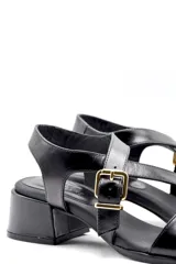 Sandalias negras con tiras cruzadas, hebilla dorada y taco ancho.