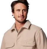 Camisa beige de corte recto, con cuello clásico, cierre frontal con botones a presión, dos bolsillos de parche en el pecho con cierre a presión y un anillo en D en el bolsillo izquierdo. Marca Columbia, colección Heritage.