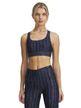 Top deportivo Under Armour con estampado floral en tonos rosa y amarillo sobre fondo negro. Cuenta con tirantes cruzados en la espalda y banda elástica con el logo de la marca en el contorno inferior.