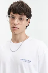 Remera blanca de manga corta con estampado en la espalda con texto en gris y diseño floral.