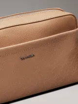 Bandolera Calvin Klein color marrón claro con estampado del logo de la marca. Tiene correa ancha ajustable, cierre de cremallera, bolsillo exterior delantero y bolsillo interior.