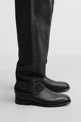 Bota Chelsea de cuero negro, con elásticos laterales, tirador trasero y suela con ligero tacón.