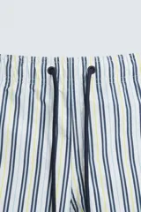 Bañador de hombre confeccionado en tejido técnico con textura. Diseño a rayas verticales en tonos azul y blanco. Cintura elástica ajustable con cordón. Bolsillos laterales y detalle de bolsillo trasero de solapa. Bajo con aberturas laterales. Forro interior.