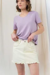 Minifalda de denim color crema con volados en los bolsillos delanteros y en el ruedo.